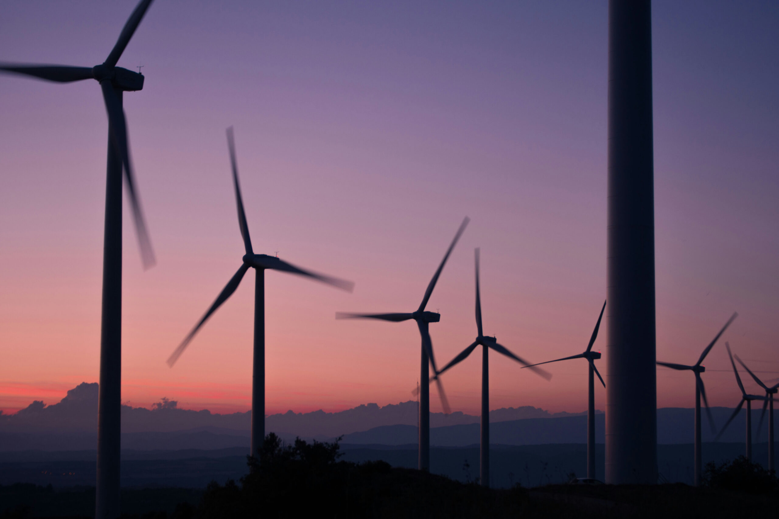 Multiple wind turbines set against a sunset sky
